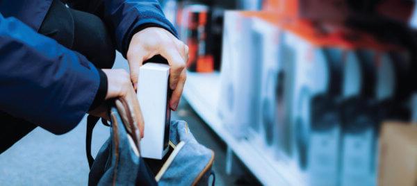 A close up of a person shoplifting an item into their bag