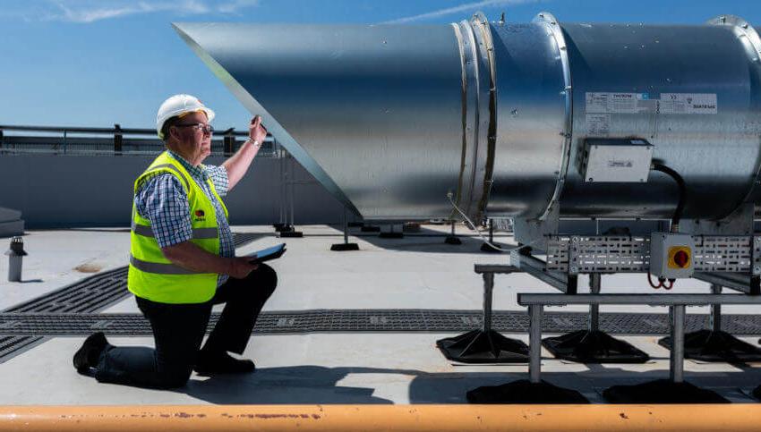 Mitie engineer in safety gear inspecting a roof vent