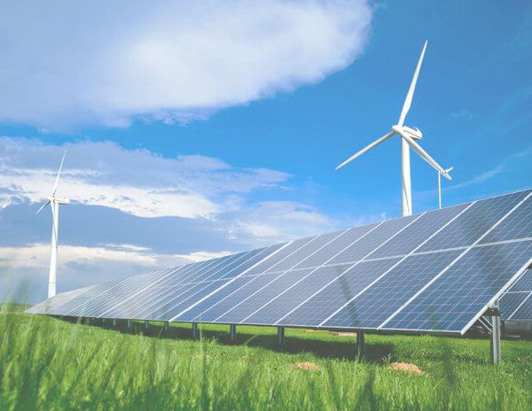 Solar energy panels and windmills against blue sky on summer day