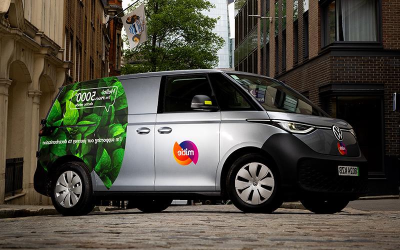 Mitie branded electric van - grey van with green leaves on the rear, with text of 'Hello! I'm Mitie's 5000th electric vehicle'