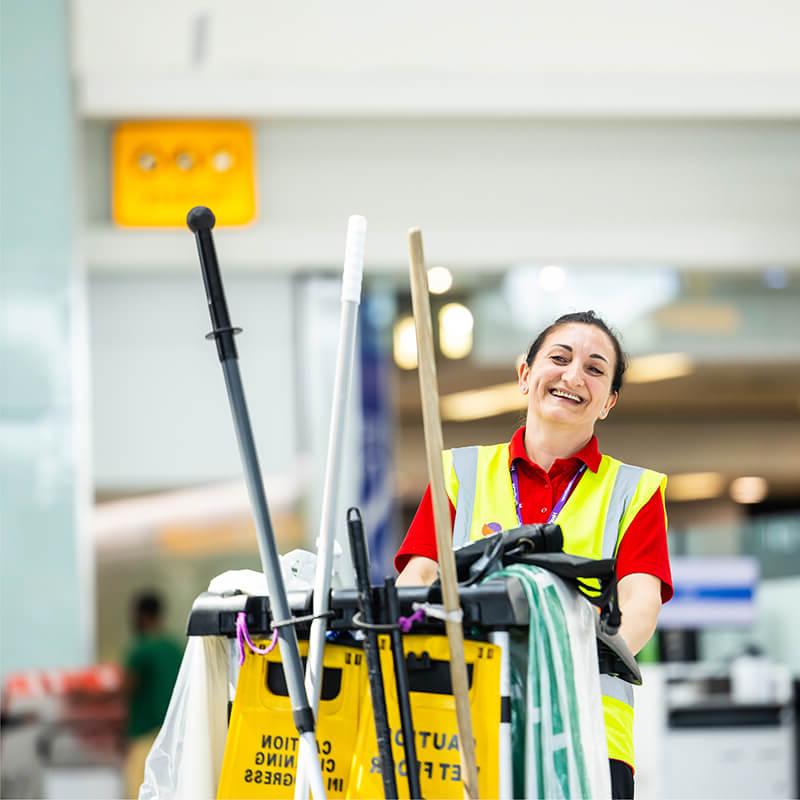 Mitie cleaner pushing a trolley of equipment and supplies